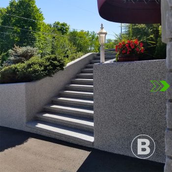 alt="Escalier extérieur avec revêtement gris texturé."