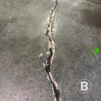 alt="Fissure visible dans une dalle de béton."